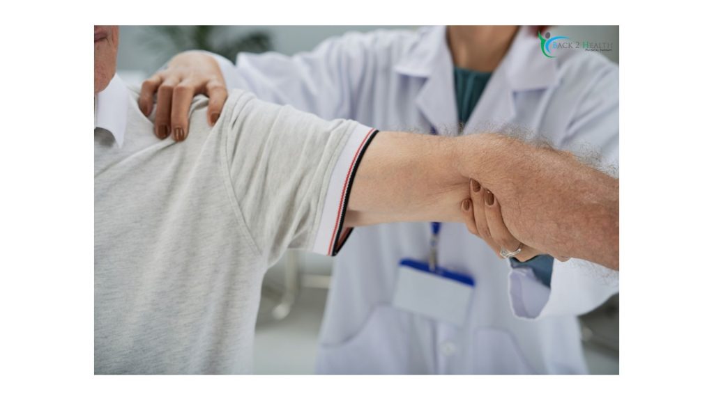 A healthcare professional at Back 2 Health clinic performing a manual shoulder mobilization and range of motion assessment on a patient.