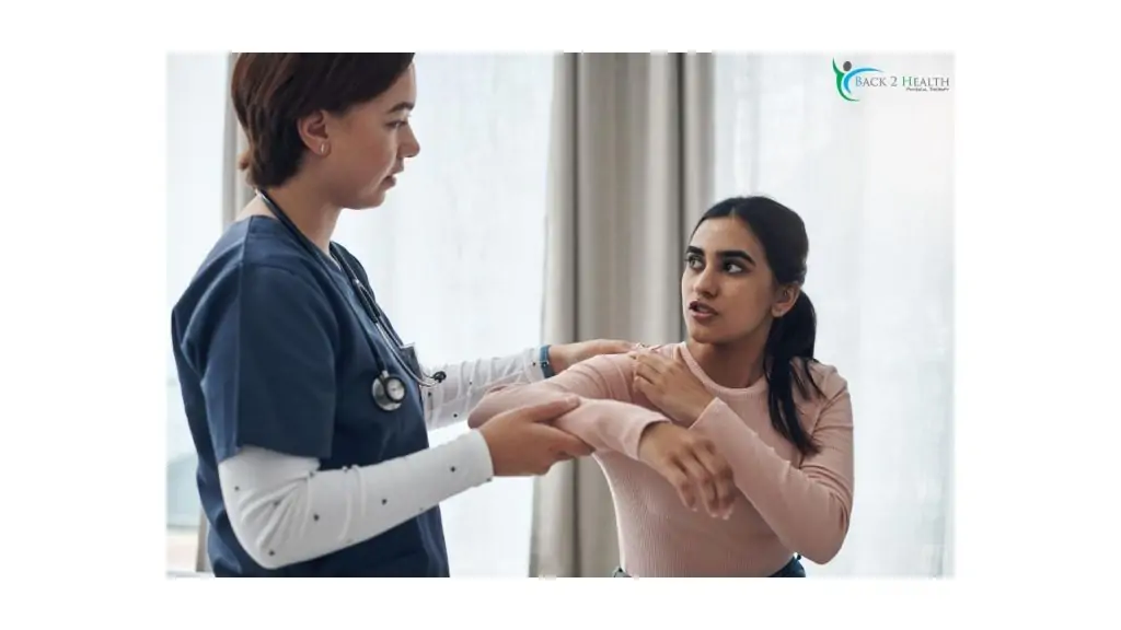 A physical therapist assisting a woman with shoulder movement during a rehabilitation session at Back 2 Health clinic
