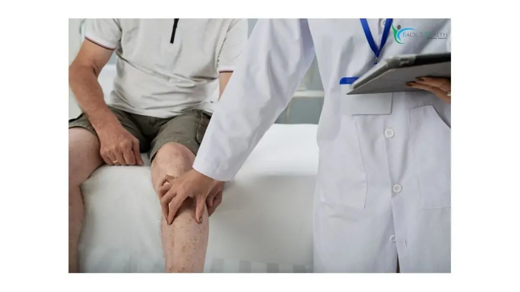 A physical therapist in a white coat examining an elderly man's knee in a clinical setting at Back 2 Health Physical Therapy.