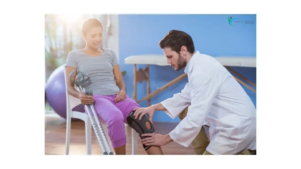 A male physical therapist in a white coat fitting a supportive knee brace on a female patient holding crutches at Back 2 Health Physical Therapy.