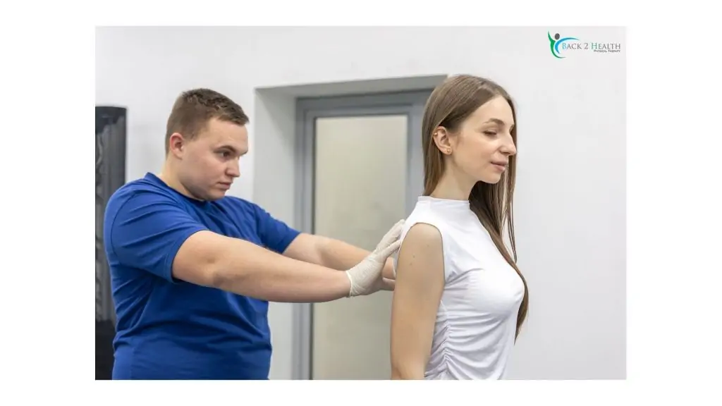 A physical therapist at Back 2 Health performs a shoulder assessment on a female patient to determine the best rotator cuff rehab exercises.